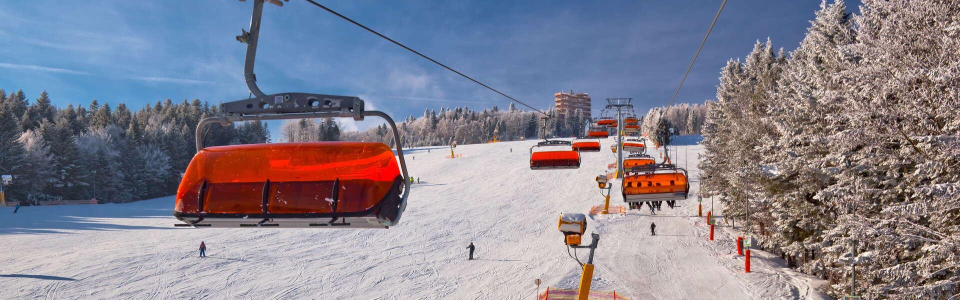 Widok na ośnieżony stok narciarski po którym jeżdżą narciarze.