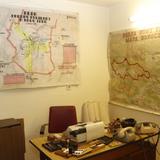 Gabinet szefa obrony cywilnej z biurkiem i mapami na ścianach.