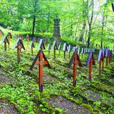Krzyże z daszkami na mogiłach w lesie na wzgórzu