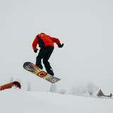 Mężczyzna skacze na desce snowboardowej.