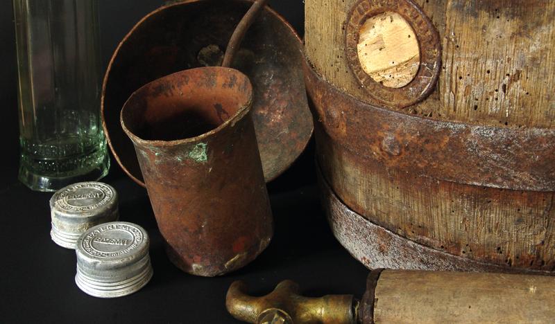 Dawne metalowe naczynia, beczka i nakrętki z dawnych butelek