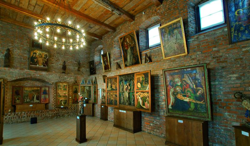 Wnętrze muzeum, obrazy wiszące na ścianach.
