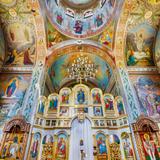 Zdobione wnętrze murowanej cerkwi. Barwny ikonostas i freski.