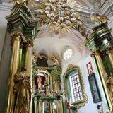 Wnętrze kościoła, bogato zdobiony ołtarz główny, piękny żyrandol, po bokach kolumny i ołtarze boczne.