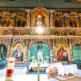 Wnętrze drewnianej cerkwi. Złocony ikonostas z ikonami. Na przodzie ołtarz.