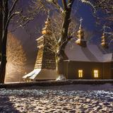 Drewniana cerkiew nocą w zimie. Pięknie oświetlona i lekko przysypana śniegiem.