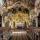 Wnętrze drewnianego kościoła, nawa główna, marmoryzowane kolumny, ławy w głębi barokowy ołtarz.