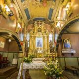 Wnętrze drewnianego kościoła - bogato zdobiony, złocony ołtarz główny z obrazem Matki Bożej z Dzieciątkiem. Na suficie i ścianach polichromia.