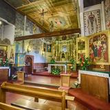 Wnętrze drewnianego kościoła, polichromowane ściany, ławki, ołtarz główny i ołtarze boczne.