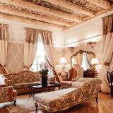 Pokój w hotelu, sofy, fotele, ława, z tyłu duże lustro, malowany, drewniany sufit.