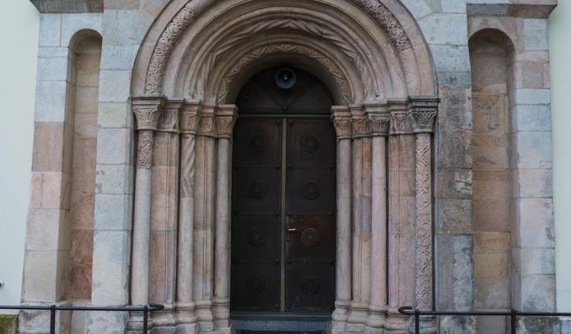 Zbliżenie na ozdobny kamienny portal w kształcie łuku, otoczony kolumnami