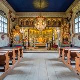 Wnętrze drewnianej cerkwi. Bogate polichromie, w głębi ikonostas i ołtarz  główny oraz po bokach ołtarze boczne i ławy.