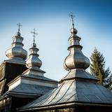 Baniaste kopuły pokryte blachą na dachu drewnianej cerkwi.