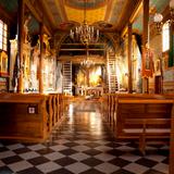 Wnętrze drewnianego kościoła. Bogate barokowe zdobienia, ławy, polichromie, w oddali ołtarz.