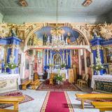 Wnętrze drewnianego kościoła. Zdobiona polichromiami nawa i prezbiterium. Barokowe ołtarze w kolorze niebieskim i złotym.