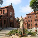 Kompleks ceglanych budynków z kościołem oraz figura Rafała Kalinowskiego