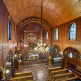 Wnętrze kościoła ze ścianami oszalowanymi drewnem. W ołtarzu obraz Matki Bożej Królowej Polski.