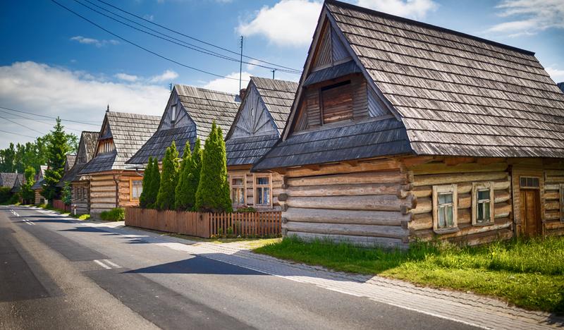 Drewniane domy z gontowymi dachami, ustawione szczytami do drogi