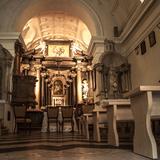 Wnętrze kościoła, nawa główna, na środku ołtarz główny zajmujący całe prezbiterium z kolumnami, posadzka, ławy i dwa ołtarze boczne.