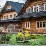 Na zdjęciu widać noclegownię Toporzysko- drewniany budek z czarnym dachem, a przed nim zagroda z trawnikiem i krzaczkami.