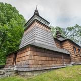 Drewniana cerkiew ze ścianami i dachem pokrytymi gontem. Do cerkwi prowadzą niewielkie schodki, otoczona jest drewnianym ogrodzeniem i drzewami.