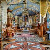 Wnętrze drewnianego kościoła z polichromiami i ołtarzami.