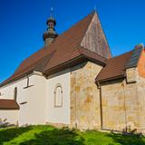 Niski kościół z kamienia, z elementami z drewna i cegły, w większości pomalowany na biało, z dachem krytym brązową dachówką.