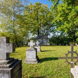 Mogiły z metalowymi węgierskimi krzyżami z kołami zębatymi i krzyżami kamiennymi na cmentarzu porośniętym trawą