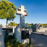 Nagrobki na cmentarzu ustawione blisko siebie, w centralnym punkcie zdjęcia nagrobek z podwójnym krzyżem