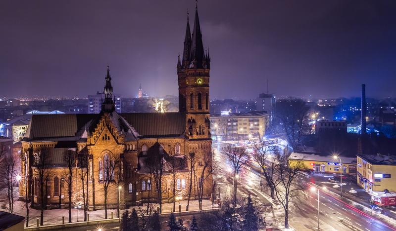 Kościół z cegły z dwiema wysokimi wieżami, widoczny nocą. ładne oświetleni całego miasta.