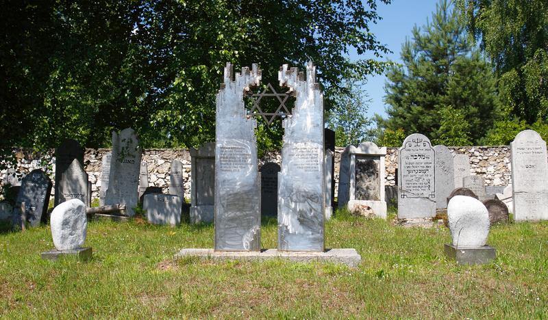Pomnik z metalową sześcioramienną gwiazdą. Za nim żydowskie kamienne nagrobki.