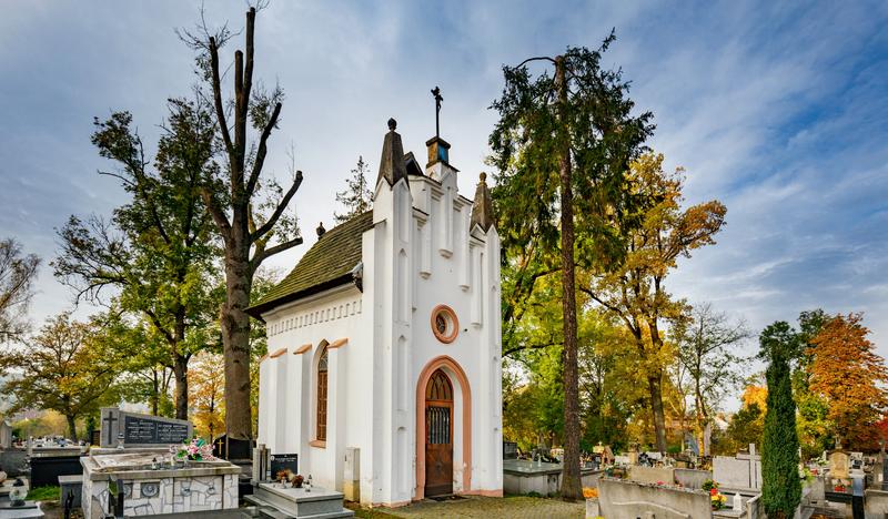 Biała wysoka kaplica, stojąca na cmentarzu.