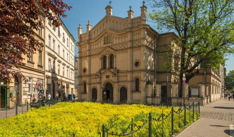 Budynek synagogi za ukwieconym skwerkiem w słoneczny dzień