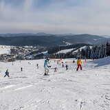 Narciarze u góry stoku narciarskim Słotwiny. Widok na góry i wzgórze otaczające stację narciarską.