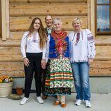 Rodzina na tle domu, osoby ubrane w stroje inspirowane tradycjami łemkowskimi