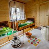 Wnętrze pokoju, stół i dwa łóżka, ściany wyłożone drewnem