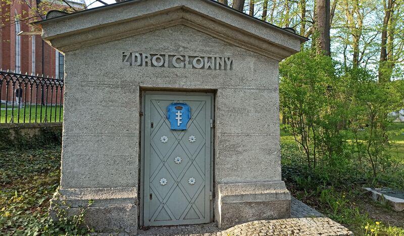 Ujęcie wody Zdrój Główny w Krzeszowicach, niewielka murowana budka z ozdobnymi drzwiami z herbem Potockich
