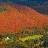 W dole na wzgórzu nad doliną widoczne ruiny zamku. Górują nad nimi zalesione góry. Krajobraz jesienny w rudych barwach.