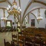 wnętrze sali gotyckiej z równo ustawionymi krzesłami, pięknymi żyrandolami i sklepieniami