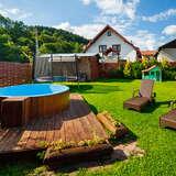 Widok ogród, po lewej basen z leżakami, za nim trampolina i domek dla dzieci. W tle dom.