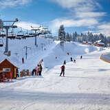 Widok na stację narciarską Henryk Ski w zimowy słoneczny dzień, po prawej stronie wyciąg orczykowy i wyciąg krzesełkowy