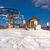 Kilku narciarzy korzystających z wyciągu krzesełkowego na stacji narciarskiej Master Ski Tylicz w zimowy słoneczny dzień