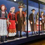 Manekiny w strojach ludowych, na przemian kobieta i mężczyzna, w Muzeum Etnograficznym w Krakowie. Wszystko znajduje się za szklaną gablotką.