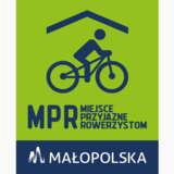 Logo MPR - na zielonym tle rowerzysta pod daszkiem. Poniżej napis dużymi literami - MPR a obok mniejszymi - MIEJSCE PRZYJAZNE ROWERZYSTOM. Pod spodem pasek granatowy z białym logo i napisem - MAŁOPOLSKA