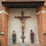 Gotycka grupa Ukrzyżowania w niszy na ścianie kościoła. Krzyż z Chrystusem i dwie figury świętych.