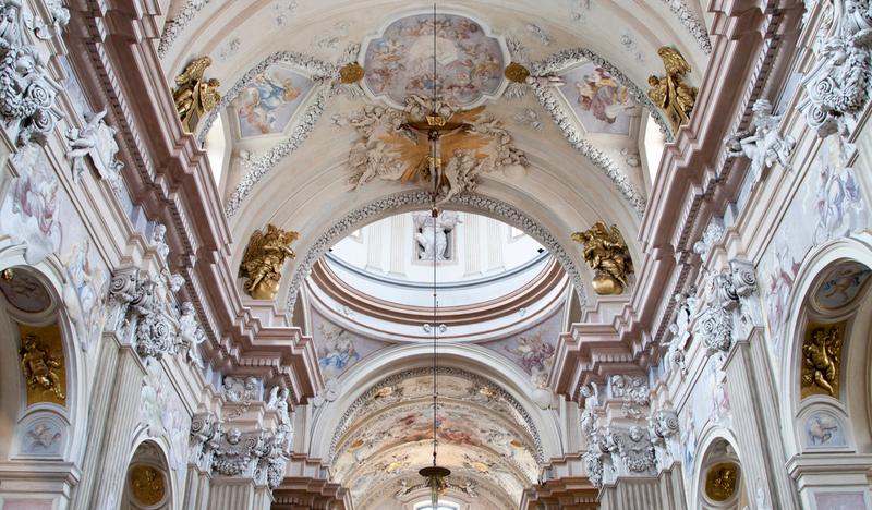 Wnętrze kolegiaty ze zbliżeniem na ołtarz główny i polichromie na stropie.