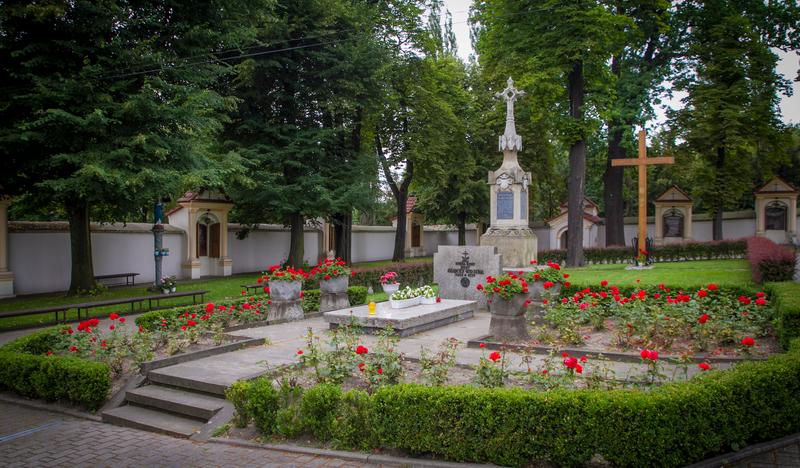 Pomnik na cmentarzu otoczony kwiatami.