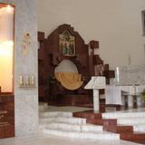 Nowoczesne wnętrze kościoła z ołtarzem z freskiem. Spływają z niego dwie wstęgi czerwonego marmuru. Po lewej figura Madonny.